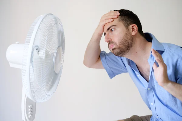 Змитий чоловік відчуває себе гарячим перед вентилятором — стокове фото