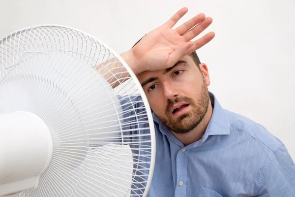 Homem corado sentindo quente na frente de um ventilador — Fotografia de Stock