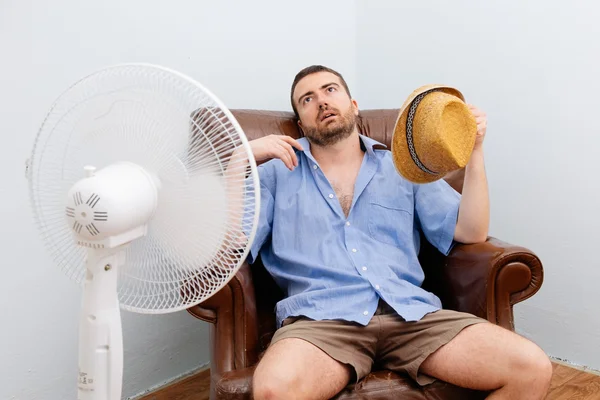 Uomo arrossato sensazione di caldo davanti a un ventilatore — Foto Stock