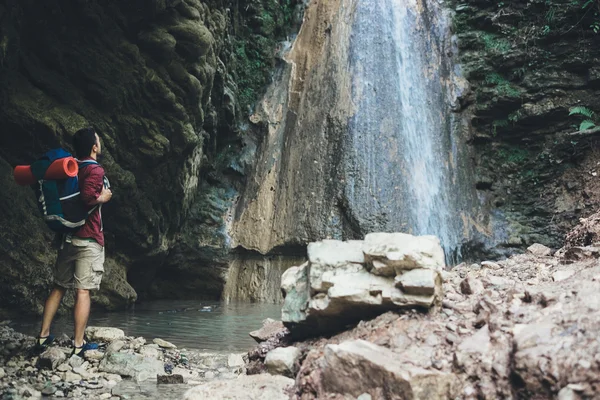 Homme à côté d'une cascade après une randonnée en montagne — Photo