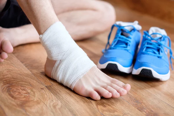 Desportista massagear seu tornozelo ferido após um acidente desportivo — Fotografia de Stock