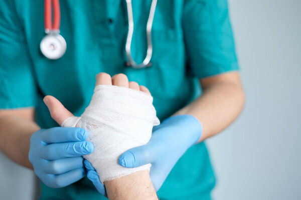 close up of doctor bandaging one hand after an accident