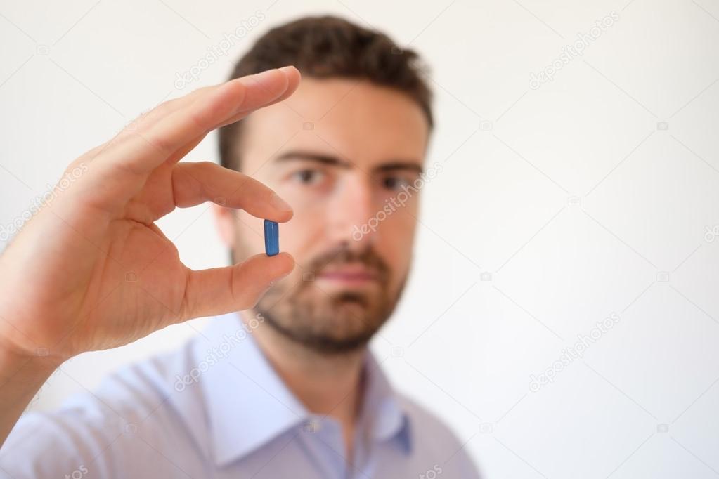 Man showing a blue pill in his hand 