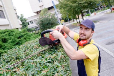 Bahçede bir çit kesme makinesi kullanarak bahçıvan