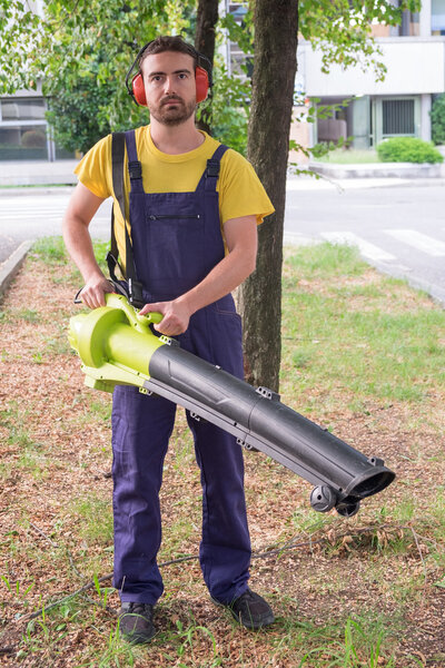 Gardener using his leaves blower in the garden