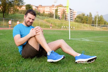 Runner çimenlerin üzerinde Yaralı diz ile