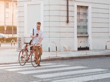 Adam caddede yürürken akıllı telefonuna bakıyor.