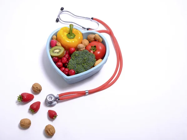 Herzförmige Schüssel mit Gemüse und Stethoskop isoliert — Stockfoto