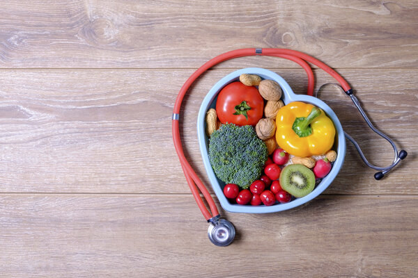Heart shaped dish with vegetables and stethoscope isolated 