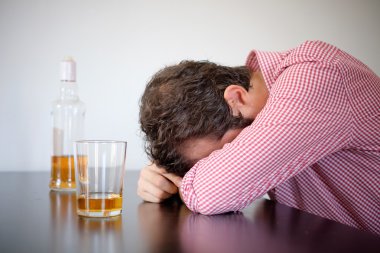 Alkol bağımlısı adam yalnız bir viski glas önünde oturmuş