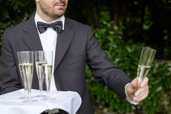 Şampanya bardağı bir tepsi üzerinde hizmet veren garson — Stok fotoğraf