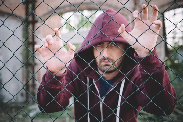 Verdrietig en onrustige jongen tegen metalen hek — Stockfoto