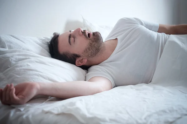 Mann schläft in seinem Bett und schnarcht laut — Stockfoto