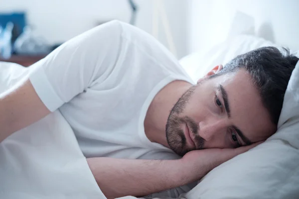 Depressiver Mann liegt in seinem Bett und fühlt sich schlecht — Stockfoto