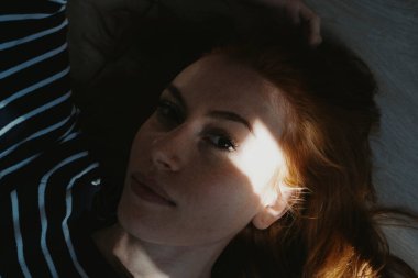 Kızıl saçlı kadın yüzü. Gölgelerle yakın.