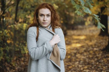 Sonbahar günü sıcak giysiler içinde dışarıda yürüyen bir kadın.