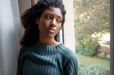 Üzgün depresif karışık ırk Afro-Amerikan pencereden dışarı bakıyor.