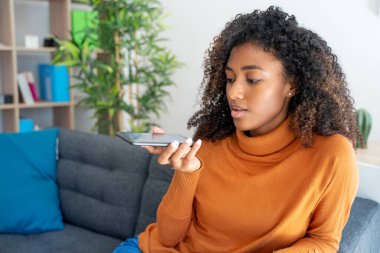 Neşeli Afrikalı kadın evde cep telefonu kullanıyor.