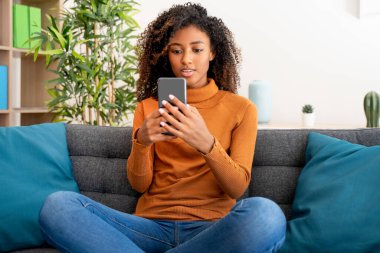 Sıradan bir genç siyahi kadın evde rahatlayıp akıllı telefondan mesaj atıyor.