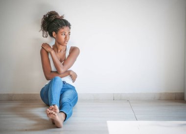 Depresyondaki genç kadın beton duvarın yanında oturuyor.