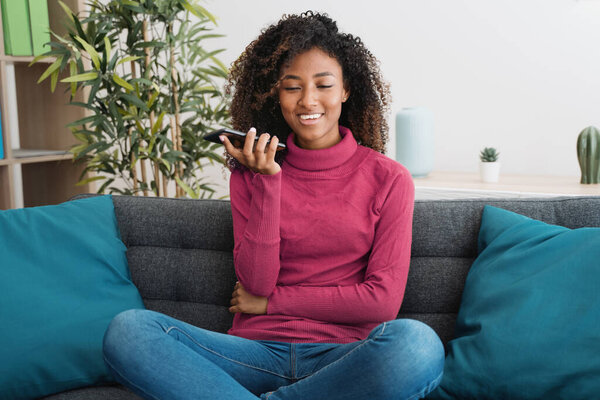 Smiling african woman using mobile phone at home