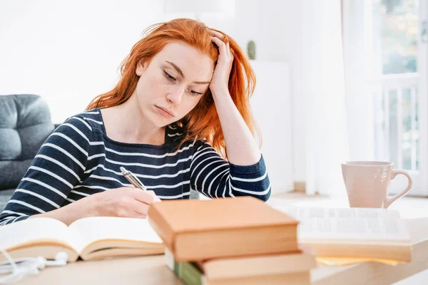 Young woman studying at home and doing homework