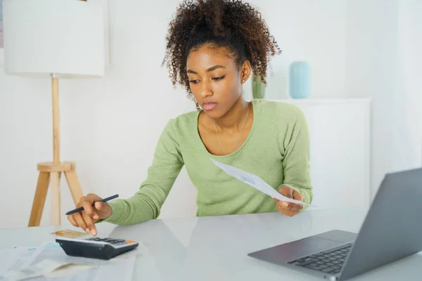 Black woman managing family budget at home table