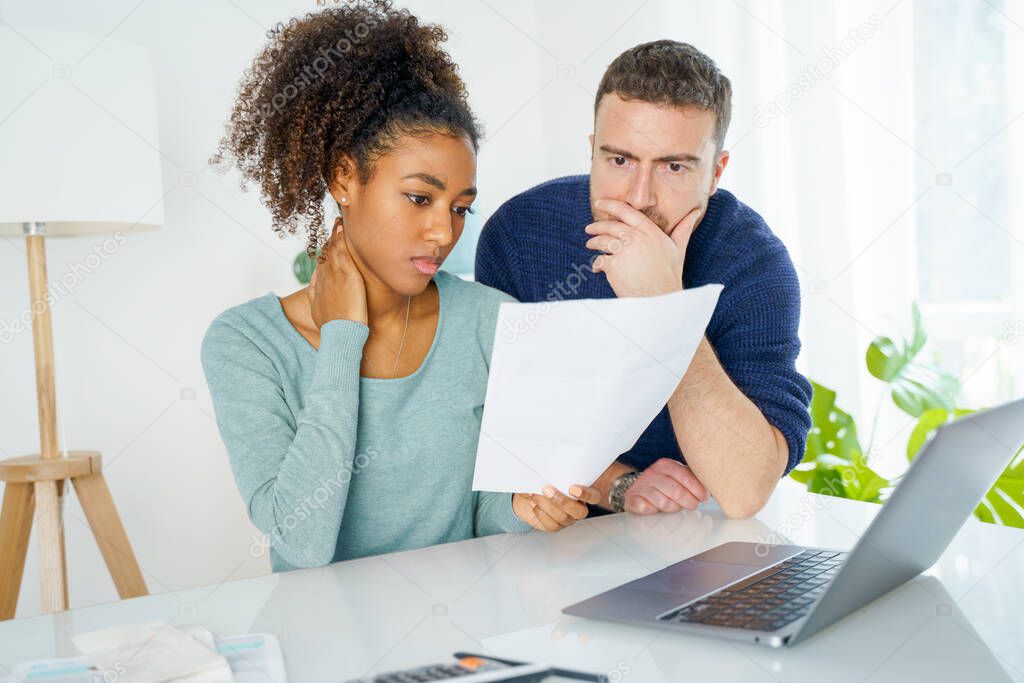 Young biracial couple with calculator looking at their finance problems