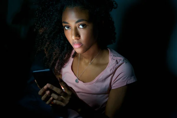 Alone young black woman using smartphone at night