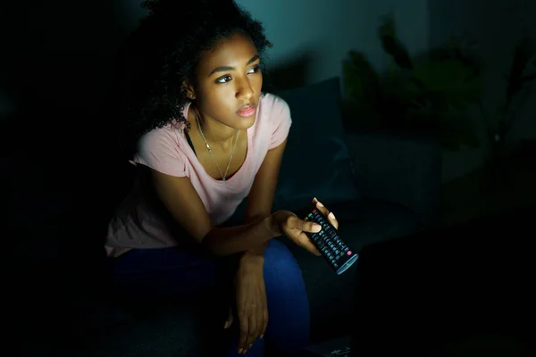 Black girl watching tv series at night at home