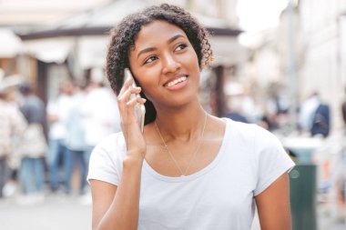 Şehir caddesinde cep telefonu kullanan siyah bir kızın portresi.