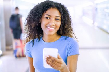 Metroda cep telefonu kullanan genç siyahi bir kadın.