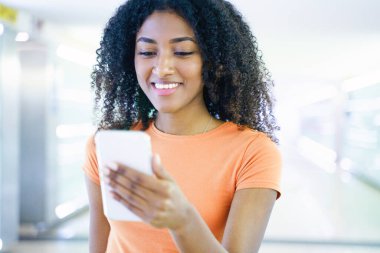 Metroda cep telefonu kullanan genç siyahi bir kadın.