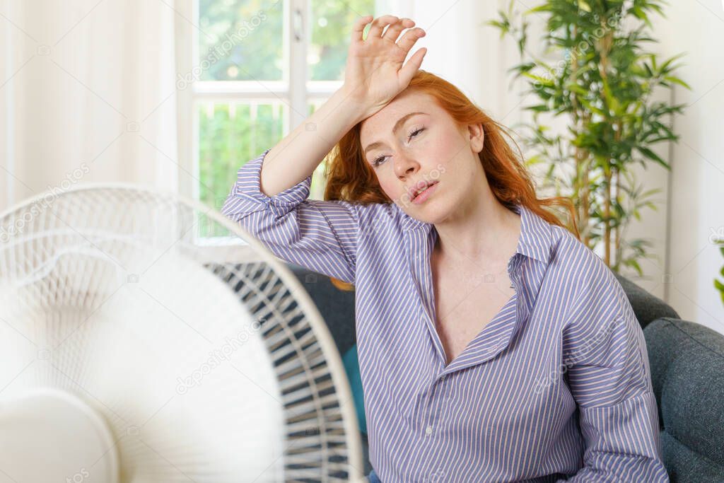 One woman tries to cool down with a fan air at home