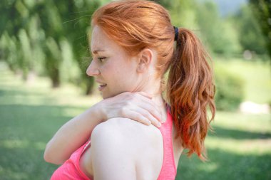One woman runner hold her injured neck and shoulder outdoor
