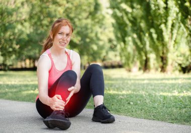 One woman runner hold her injured calf and ankle outdoor
