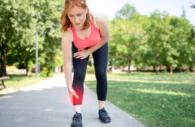 One woman runner hold her injured calf and ankle outdoor