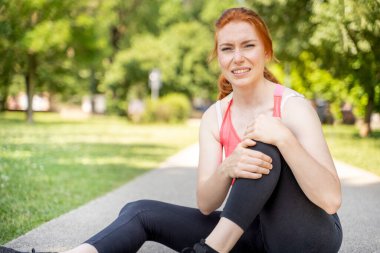 One woman runner hold her injured leg and knee