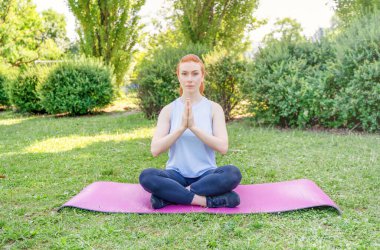 Portrait of young woman practicing yoga in public park
