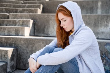 Kapüşonlu sweatshirt giyen üzgün bir kız portresi.