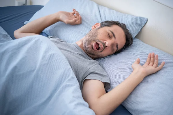 Man snoring loudly in his bed while sleeping