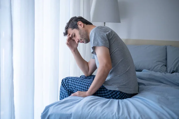 Depressed man in the morning seated on bed