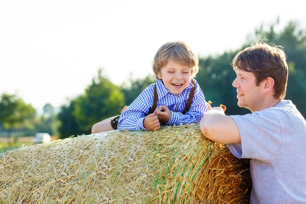 Padre e hijo pequeño se divierten en el campo de heno amarillo en verano —  Fotos de Stock