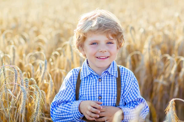 Funny little kid boy in leather shors, walking  through wheat fi — Stock Photo, Image