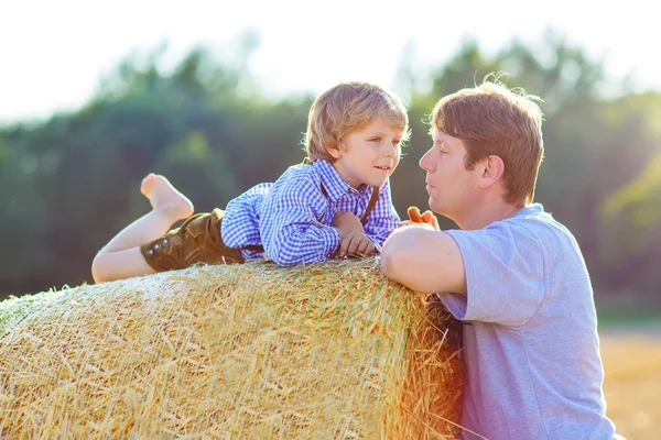 Père et petit fils s'amusent sur le champ de foin jaune en été — Photo