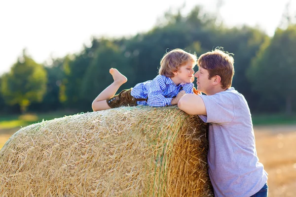 Father and little son having fun on yellow hay field in summer — Stock Photo, Image