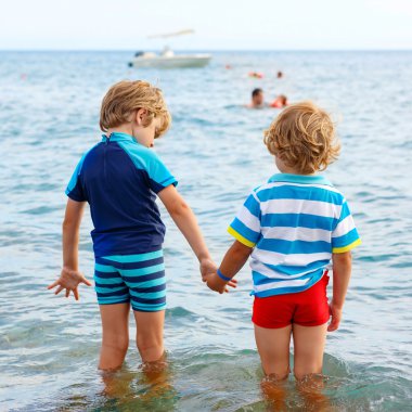 Two little kid boys taking bath in ocean