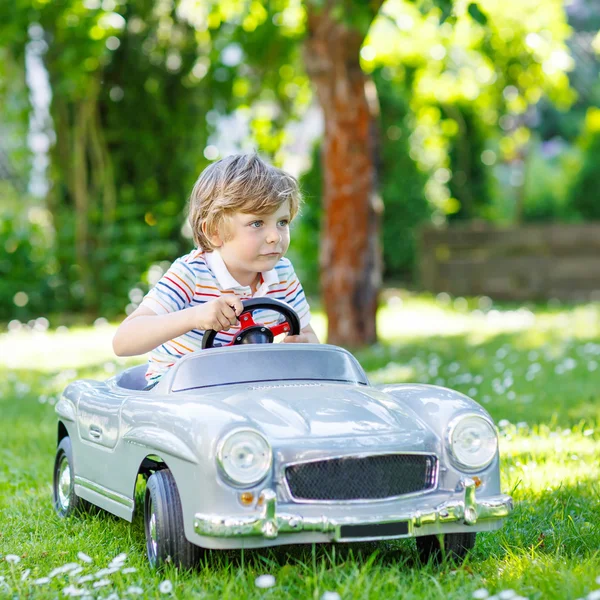 Kid boy dirigindo com grande carro de brinquedo ao ar livre — Fotografia de Stock