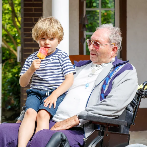 Kid boy and grandfather on wheelchair eating ice cream — Stock Photo, Image