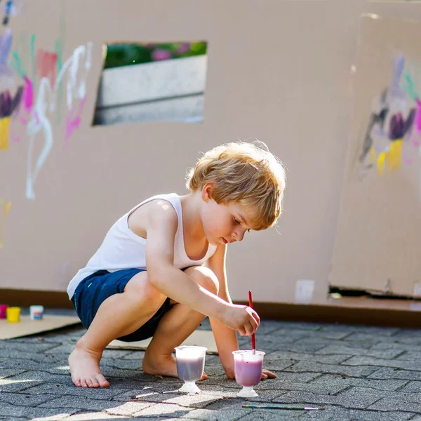 Little kid boy painting big paper house with colorful paintbox — Stok fotoğraf